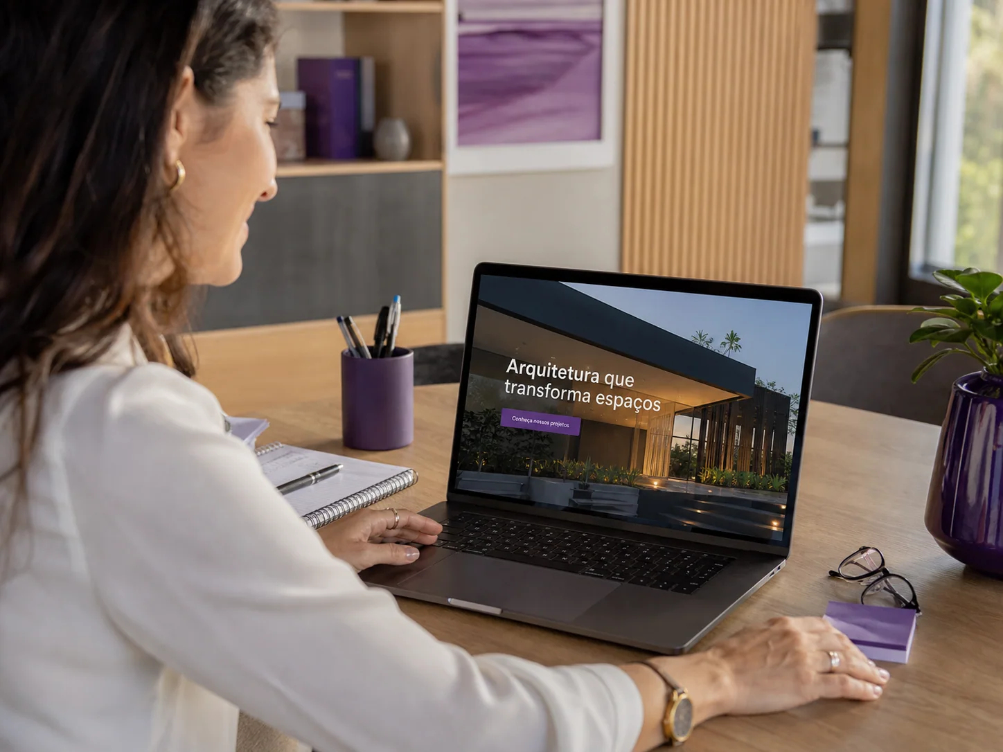 Empresária acessando no notebook um site profissional de arquitetura em português
